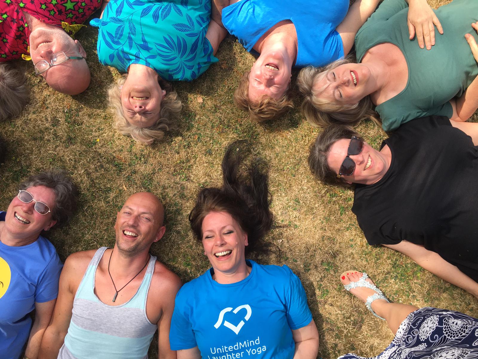 8 people laying in the grass laughing